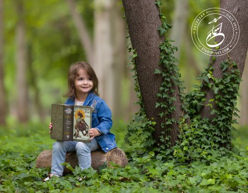 عکس کودک فضای باز درحال کتاب خواندن